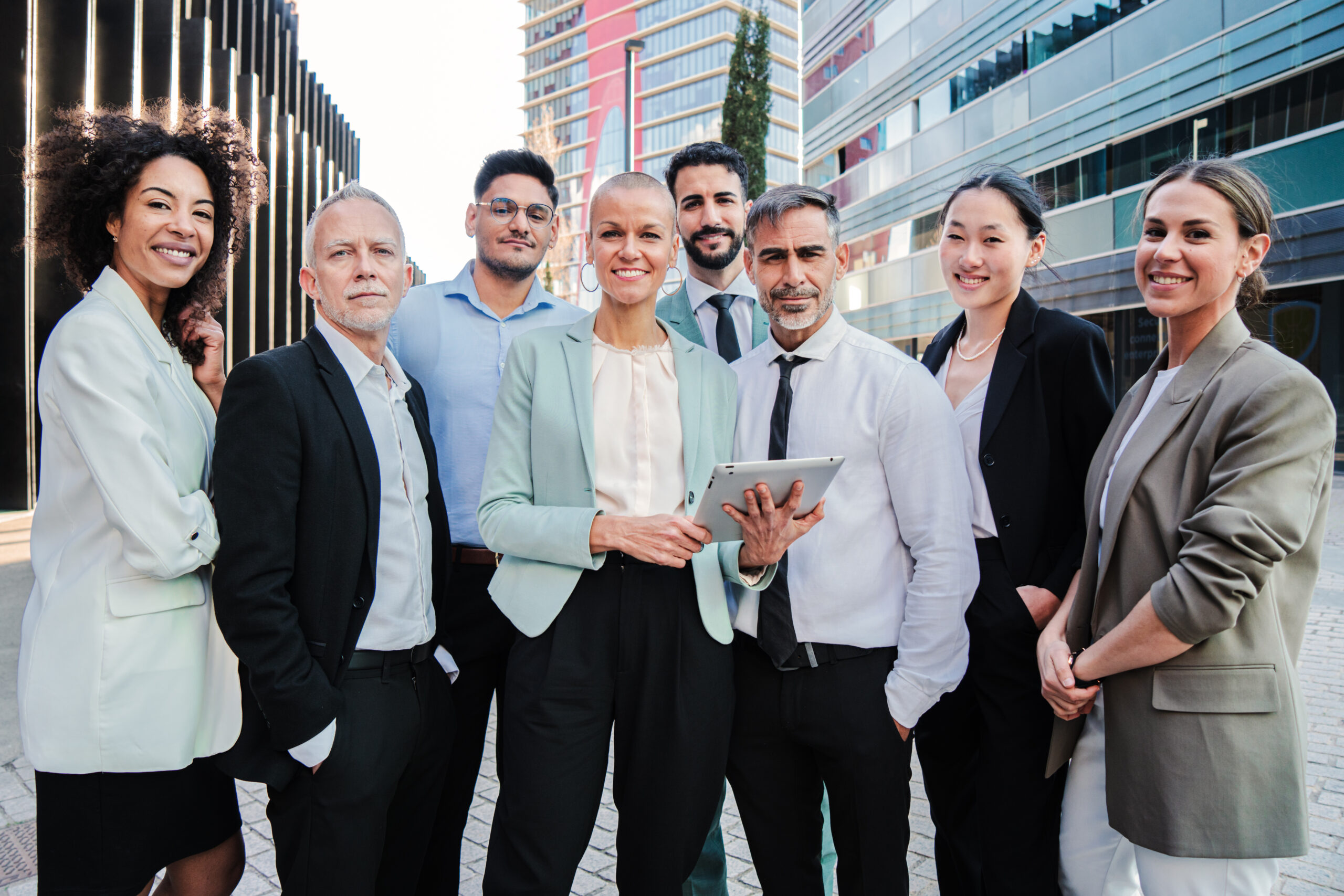 Divers team van kantoormedewerkers poseert buiten voor modern gebouw